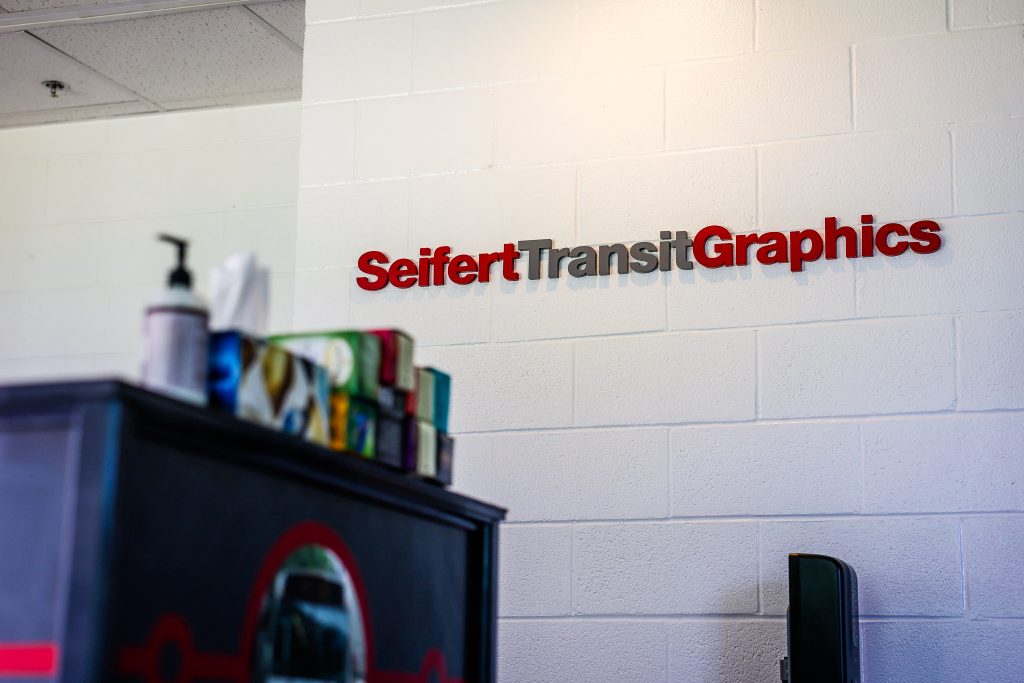 Seifert Transit Graphics logo in the lobby of our Oriskany office against a wall